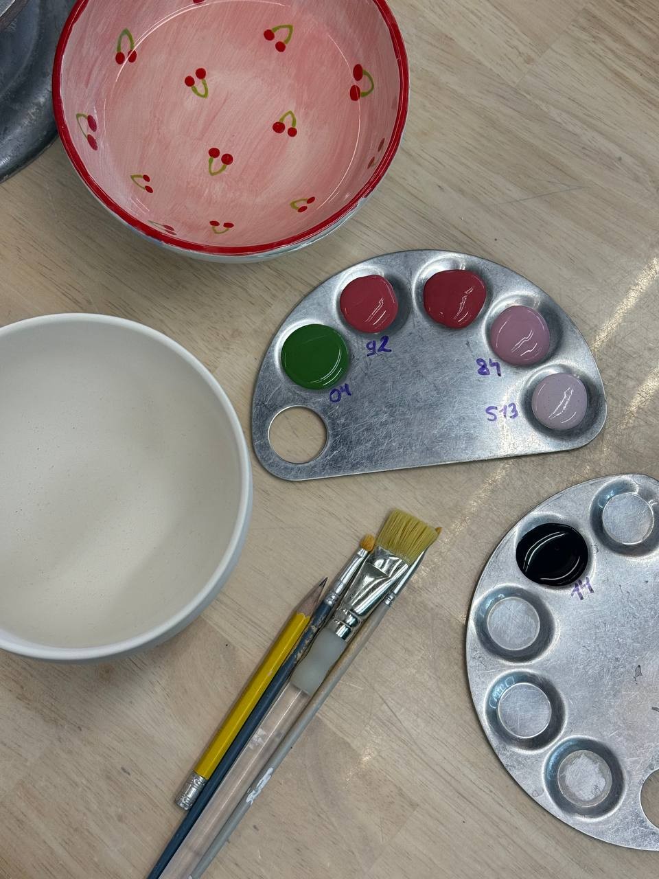Paint pots, brushes and a palette on a table